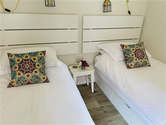 Twin beds with white bed linen and green cushions